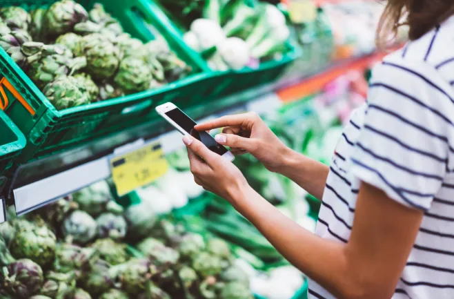 Kobieta korzystająca z telefonu w sklepie z warzywami