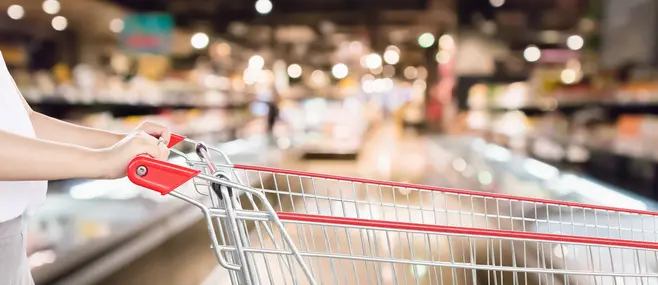 A shopping cart against the backdrop of a supermarket aisle