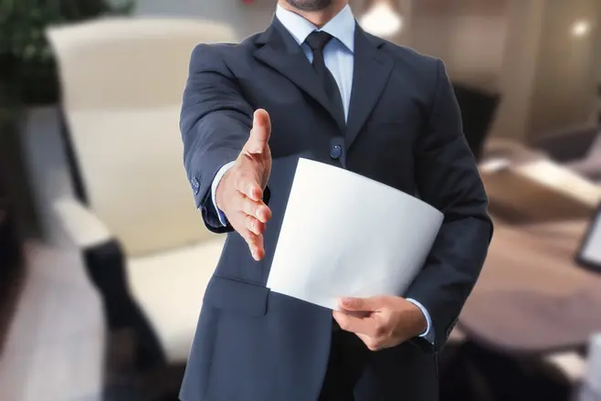 A man in a suit extending his hand in greeting