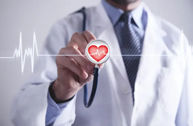 A doctor in a white coat holding a stethoscope with a heart shape