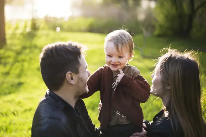 aA child surrounded by their parents