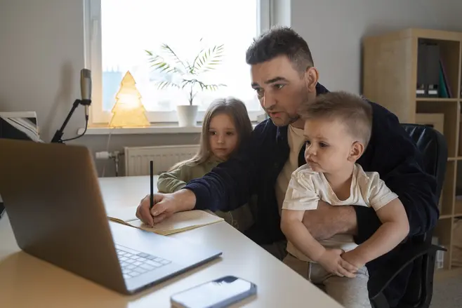 Mężczyzna podczas pracy na komputerze zajmuje się dwójką dzieci