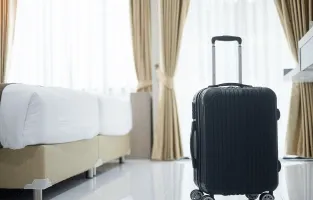 Pokój hotelowy z walizką na pierwszym planie.
