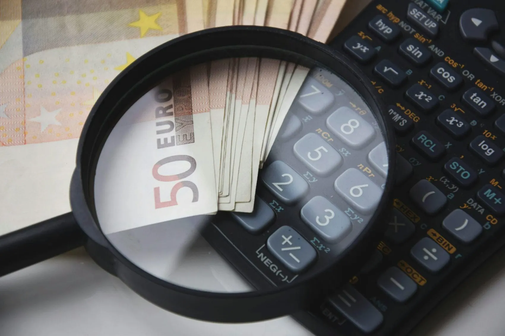 Plik banknotów Euro, lupa i kalkulator